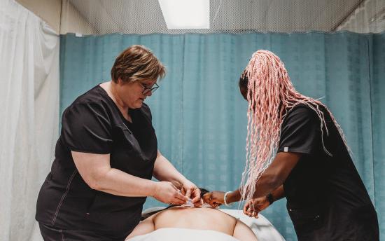 A massage therapy student practicing the art of hot rocks